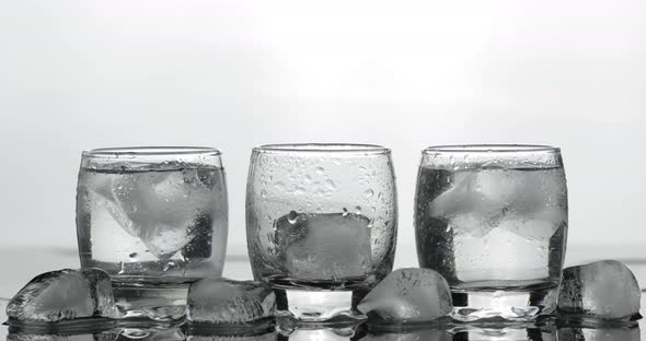 Pouring Up Shot of Vodka From a Bottle Into Glass. White Background