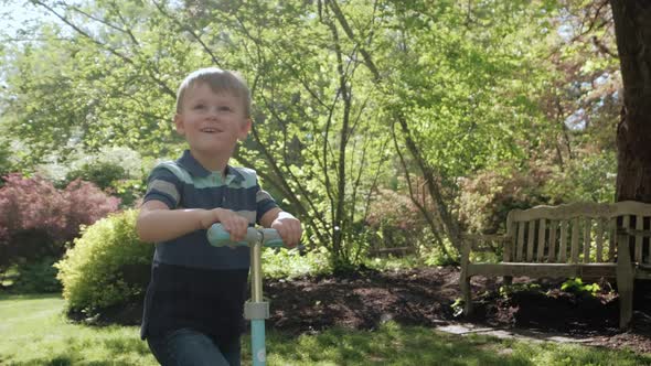 Little Boy Rides Scooter in the Park on Sunny Day