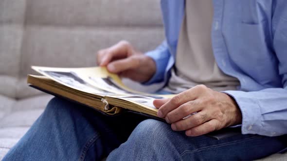 An Elderly Man's Hands are Holding an Old Photo Album