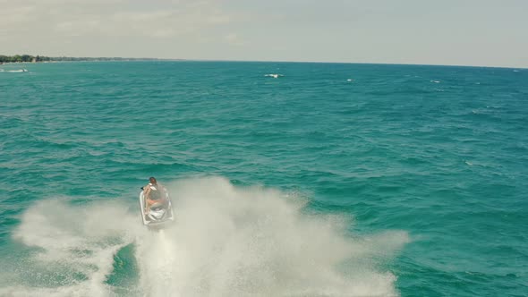 Aerial Drone Following Shot of a Couple on a Ski Jet Driving Through Waves