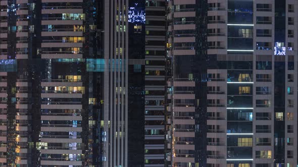 Windows of the Multistorey Building of Glass and Steel Lighting Inside and Moving People Within