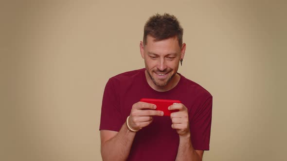 Worried Funny Young Man Winner Enthusiastically Playing Racing or Shooter Video Games on Smartphone