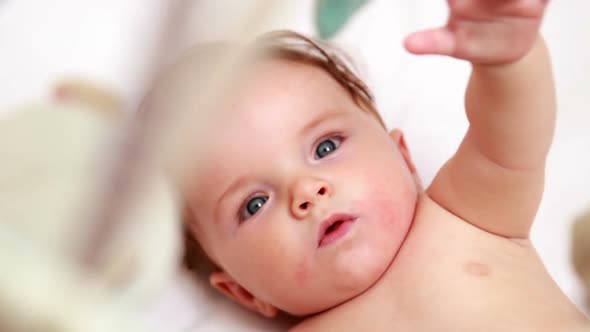 Cute baby playing with mobile in his crib