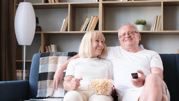 Elderly Couple of Sports Fans Watching Sports TV Games Sitting Together on the Couch