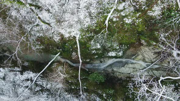 Stream of Water Flowing Among the White Rocks in the Forest in Winter