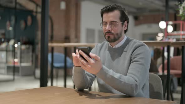 Attractive Young Man Using Smartphone in Office