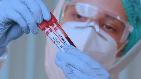 Concerned Female Doctor Analyzing Blood Test Tube of Coronavirus