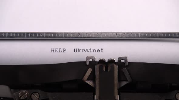 Typing phrase "HELP Ukraine !" on retro typewriter.