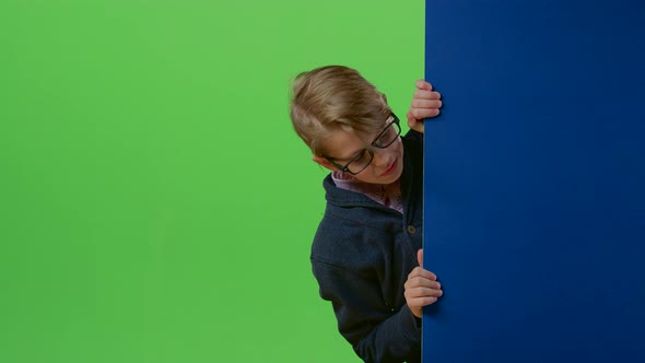Child Boy Appears From the Side of the Board Holding Her Hands in Front on a Green Screen