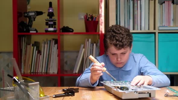 Child repairs chip and solders printed circuit board with soldering iron.