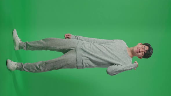 Full Body Of Man Pointing To The Back Behind By Thumbs Up While Standing In Front Of Green Screen