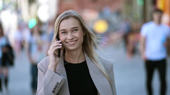 Portrait of Trendy Woman Walking on City Streets and Having Smart Phone Chat