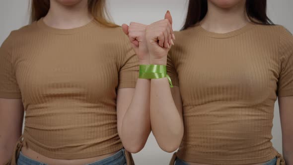 Two Slim Unrecognizable Women Raising Hands Tied with Ribbon