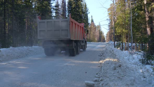 A Truck Carrying Ore Rides Along a Winter Forest