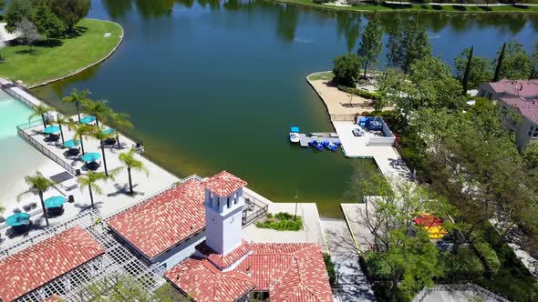 Aerial pan up looking over lake clubhouse to condos with mountains in background