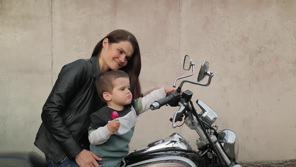 Young Mother Shows Her Son How To Turn On The Buttons On Her Motorcycle