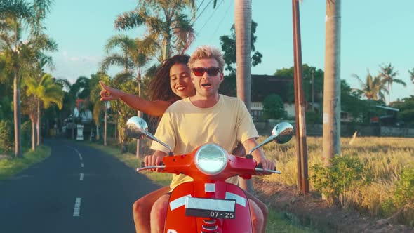 Young Couple in Love is Riding Retro Moped on Road in Tropics