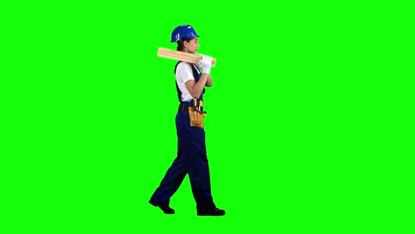 Construction Worker Wearing a Helmet Carries Three Wooden Boards. Green Screen. Side View