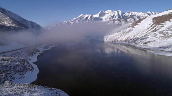 Aerial view flying backwards over winter landscape through thin clouds