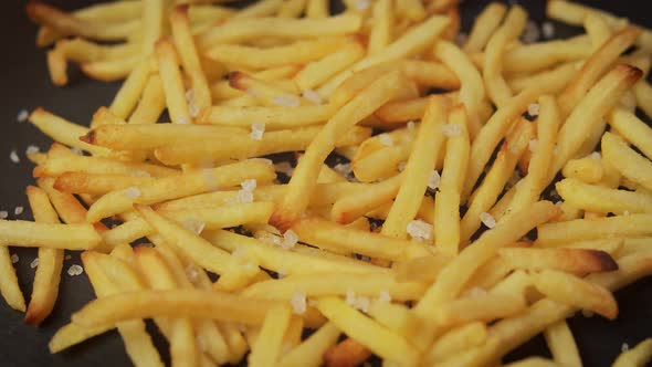 Delicious Golden Fries on a Black Table with Salt Crystals