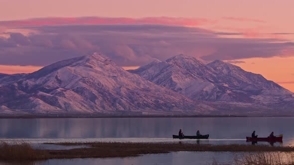 People in canoes floating on Utah Lake during colorful sunset