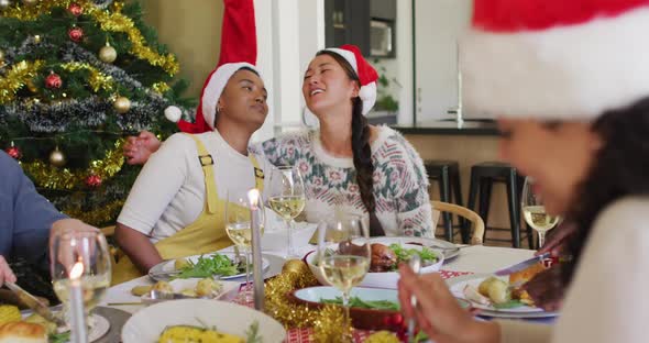 Two diverse female friends celebrating meal with friends at christmas time