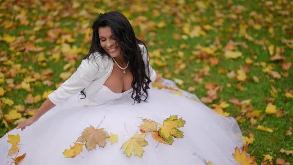 Happy Bride in Autumn Beautiful Busty Woman in White Dress is Sitting on Lawn