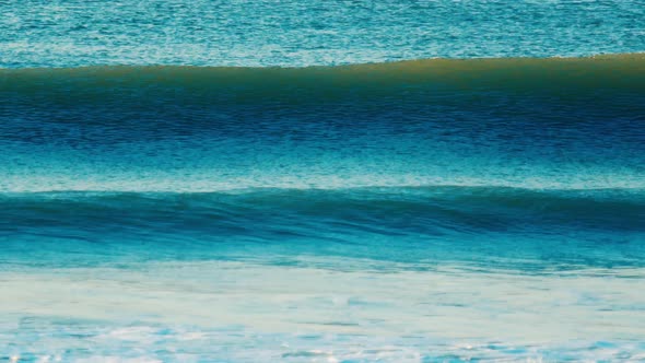 Ocean Wave Breaks on the Shore During Sunrise