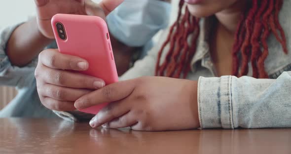 Two Afro Women Use One Smartphone in a Pink Case