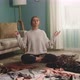 Beautiful Woman is Sitting on Floor Among Scattered Dresses and Meditates - VideoHive Item for Sale
