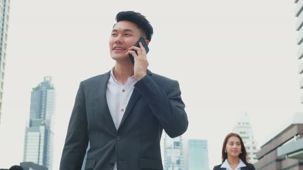 Asian young smart businessman talking in telephone in city walking outdoor to working office.
