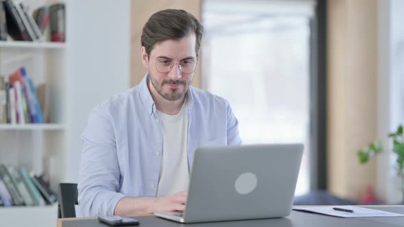 Successful Man in Glasses Celebrating on Laptop in Office