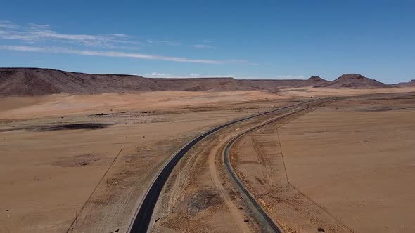 A single car is driving on a highway across the Namib desert, aerial shot