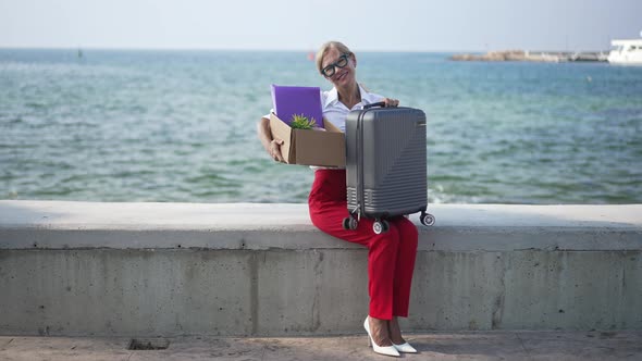 Wide Shot of Happy Gorgeous Woman Smiling Looking at Camera Sitting on Mediterranean Sea Embankment