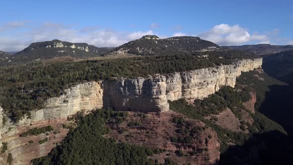 Aerial of Tavertet Cliffs with mountain landscape in background, zooming shot