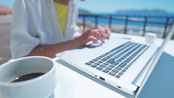 Woman Typing on Laptop Keyboard Outdoors on Terrace with Beautiful Sea View