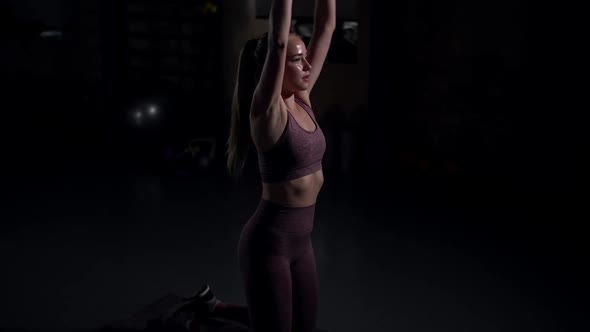 Side View Portrait of Concentrated Motivated Sportswoman Standing on Knees Raising Hands with