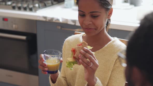 Handsome African girl eating sandwich and talking with her father