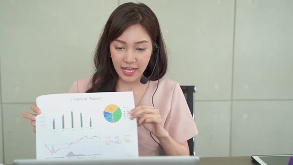 Young Asian business woman is giving a presentation to online conference for business information.