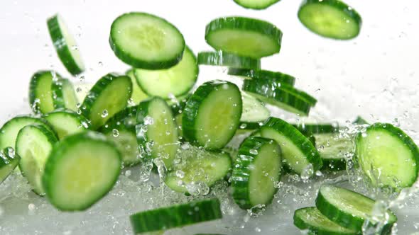 Super Slow Motion Shot of Cucumber Slices Falling Into Water on White Background at 1000Fps