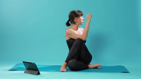 Fit Adult Following Pilates Lesson on Tablet to Stretch Body