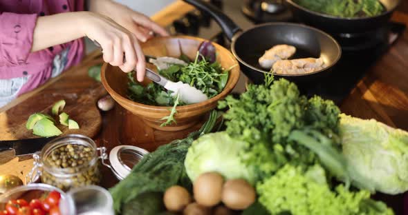 Woman Mixing Salad with Arugula and Beetroot Leaves