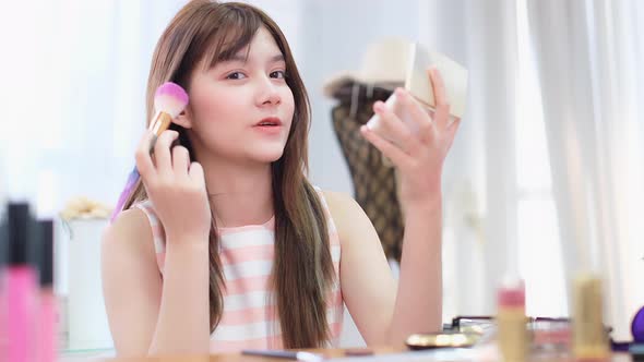 Portrait of young asian woman review cosmetics product fan following channel