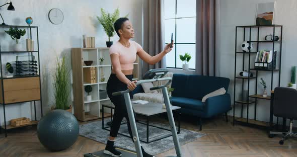 Woman in Sportswear Training on Running Track at Home and Enjoying Video Chat on Mobile