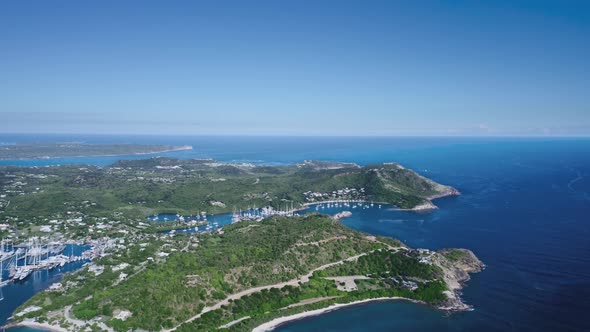 Hilly island with vegetation and marina with yachts from a bird's eye view in Antigua and Barbuda