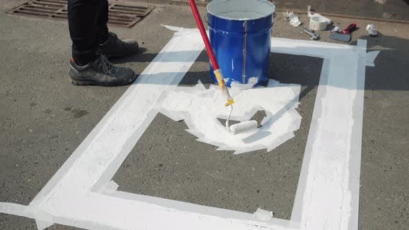 Male Worker Painting White Marking Line of Disabled Parking Lot Sign on Asphalt