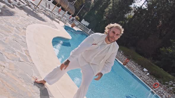 Man Dancing In White By Outdoor Swimming Pool