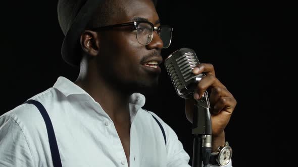 Man Singer in Half of the Turnover Sings Into a Microphone and Dance. Black Background. Close Up