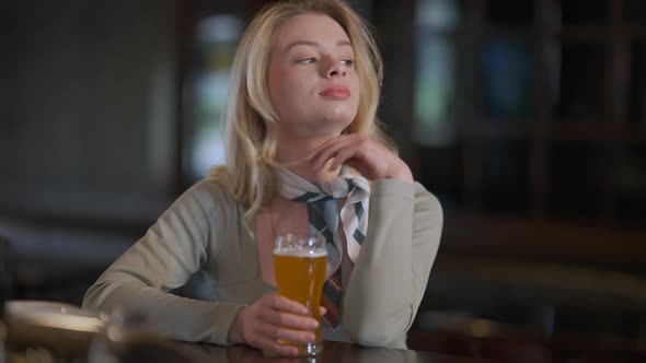 Gorgeous Slim Caucasian Young Woman Sitting at Bar Counter with Glass of Pale Lager