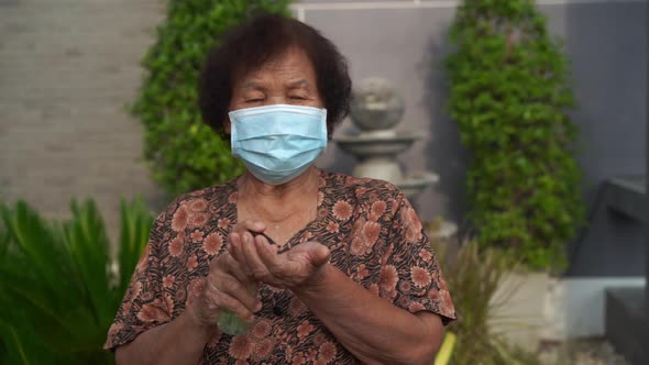 slow-motion of senior woman wearing in medical mask(surgical mask) using alcohol gel to washing hand